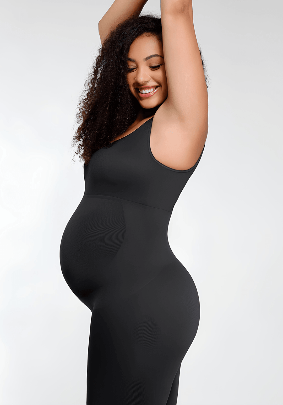 Smiling pregnant woman in a maternity catsuit posing comfortably in a black outfit