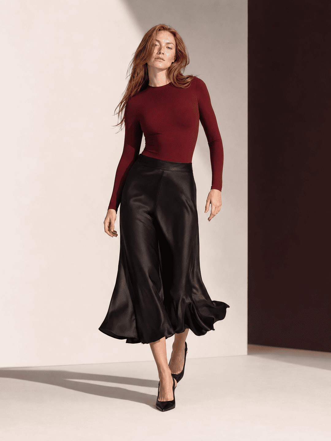 Model wearing a seamless long sleeve bodysuit paired with a flowing black skirt, showcasing stylish elegance.