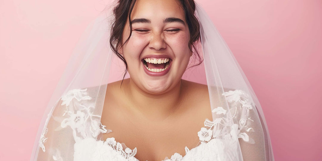 plus size wedding dresses bride smiling in lace gown and veil against pink background