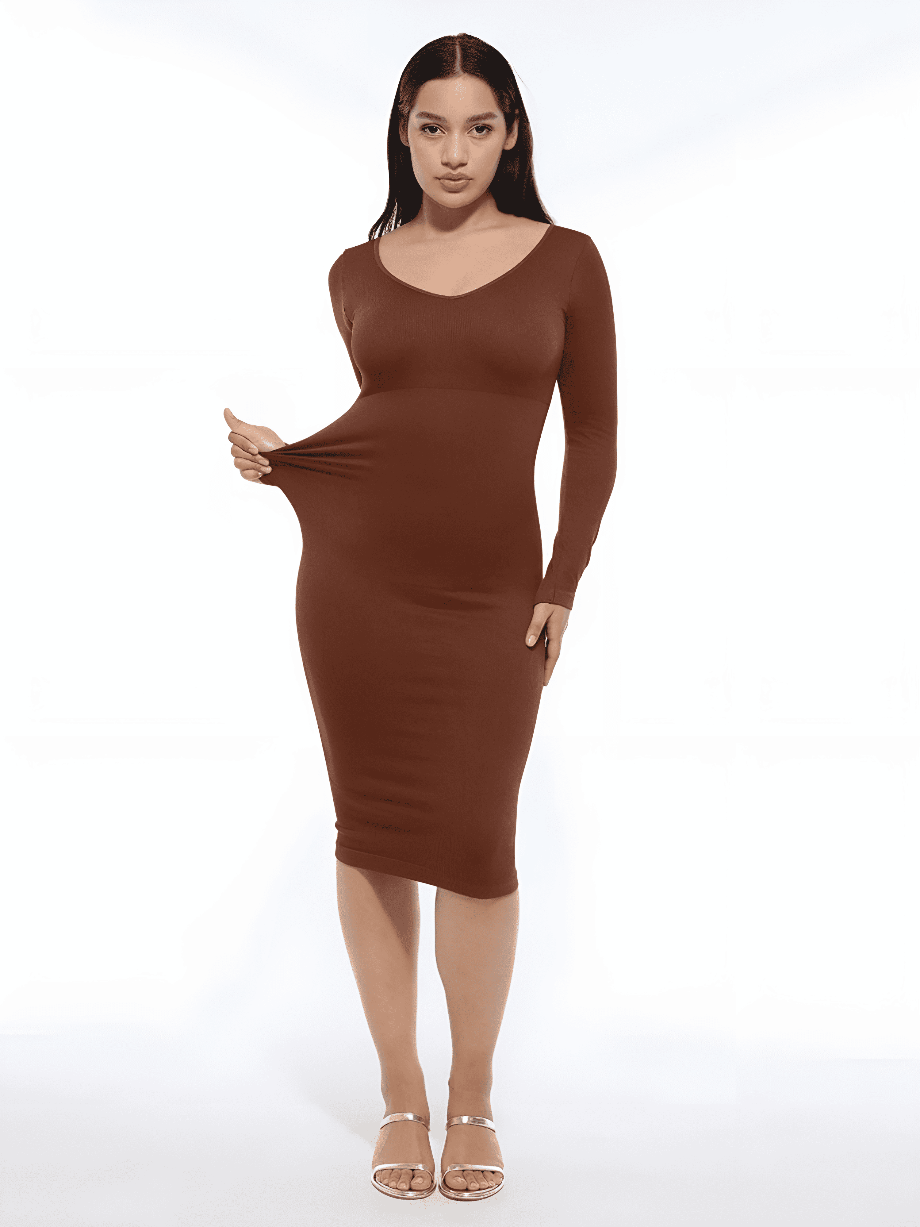 Woman in a fitted brown long-sleeve midi dress pulling the fabric, shown against a white background