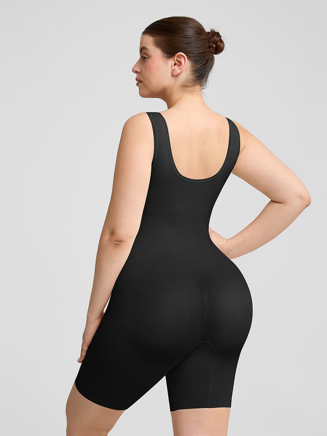 Person wearing a black bodysuit against a gray background