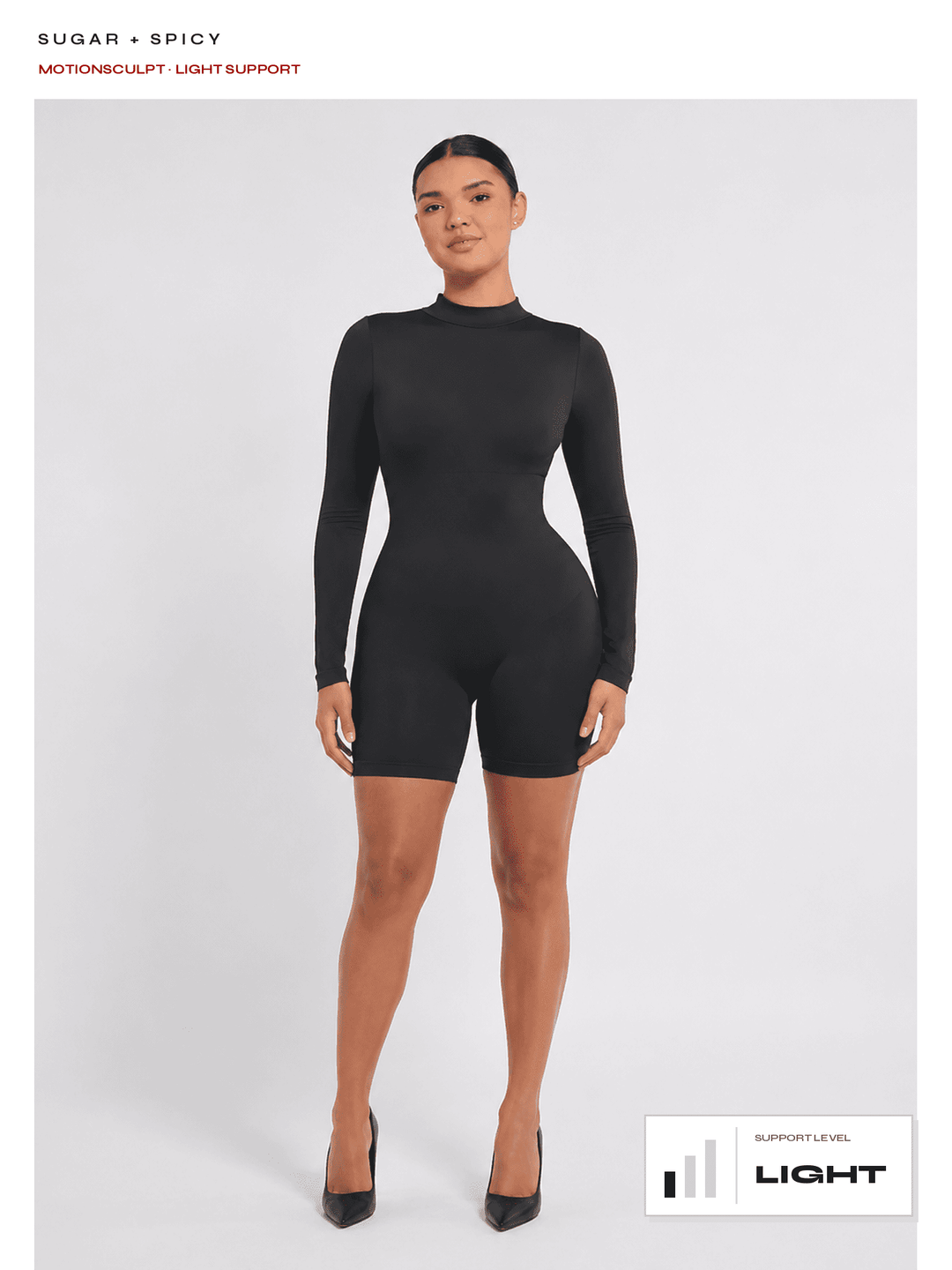 A model wearing a black long-sleeve biker shorts bodysuit with a mock neck, standing against a light gray studio background. Text at the top reads 'SUGAR + SPICY' and 'MOTIONSCULPT LIGHT SUPPORT', with a 'LIGHT SUPPORT LEVEL' graphic at the bottom right.