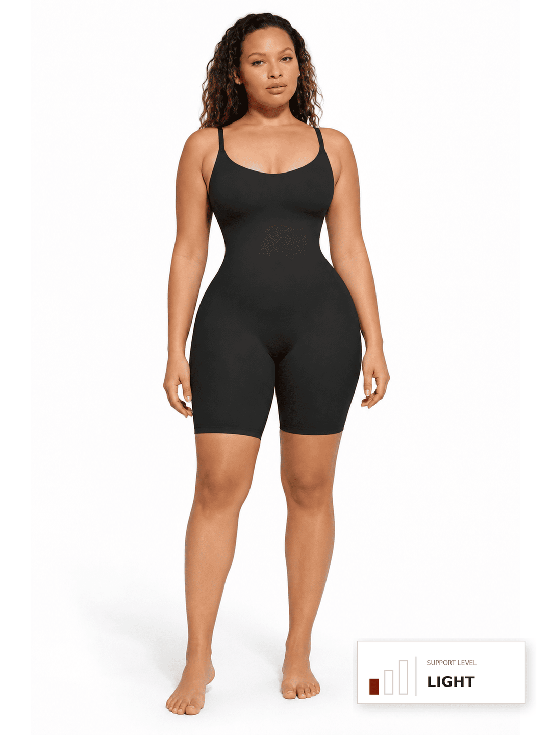 A woman modeling a black bodysuit with shoulder straps and fitted biker shorts against a plain white studio background. A small color indicator label appears in the bottom right corner.