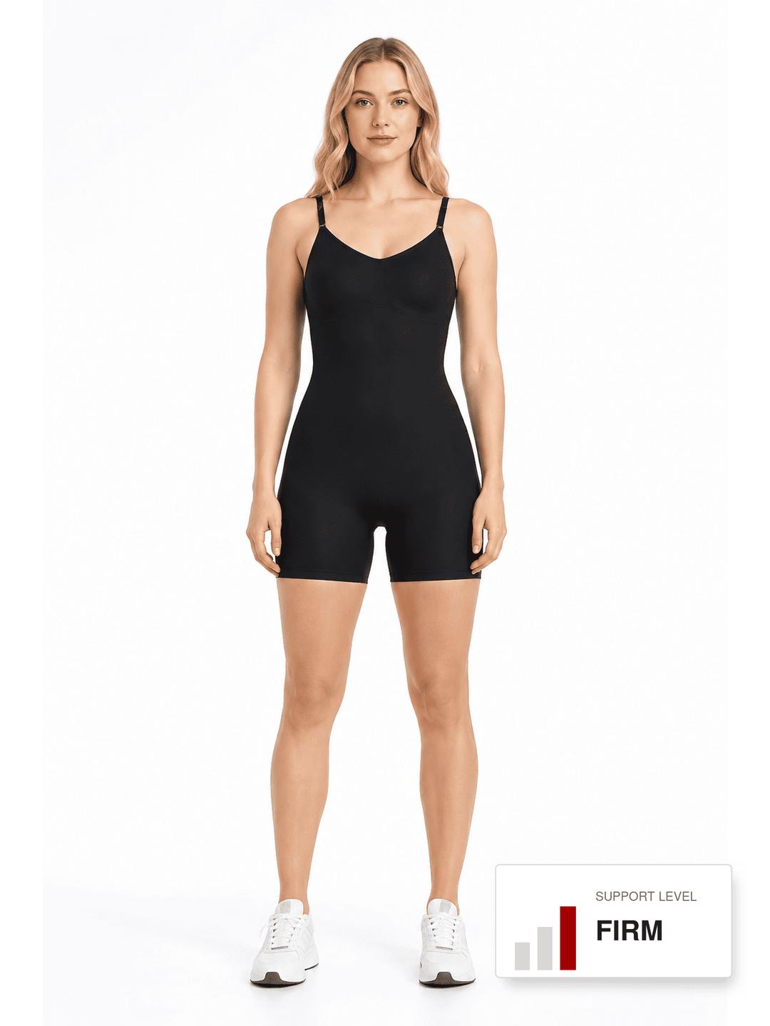 A woman modeling a black seamless shapewear bodysuit with thigh-high shorts and thin shoulder straps, paired with white sneakers, against a plain white background. A graphic label in the bottom right corner reads 'SUPPORT LEVEL FIRM'.