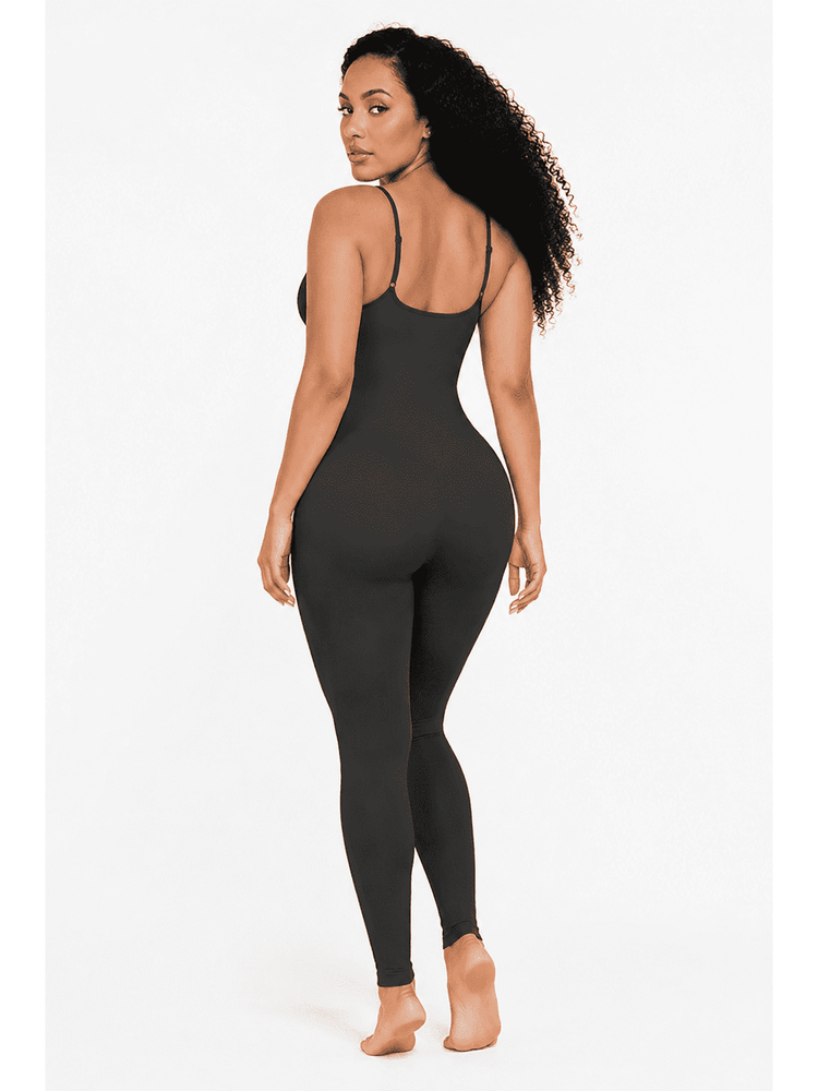 A woman modeling a black full-body slip dress or bodysuit with thin spaghetti straps, shown from a rear three-quarter angle against a plain white studio background.
