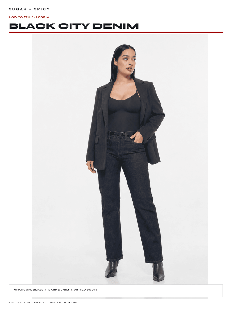 A model wearing a black denim outfit consisting of a charcoal blazer, dark denim pointed boots, and a black camisole, standing against a white studio background. The brand name 'BLACK CITY DENIM' is displayed at the top.