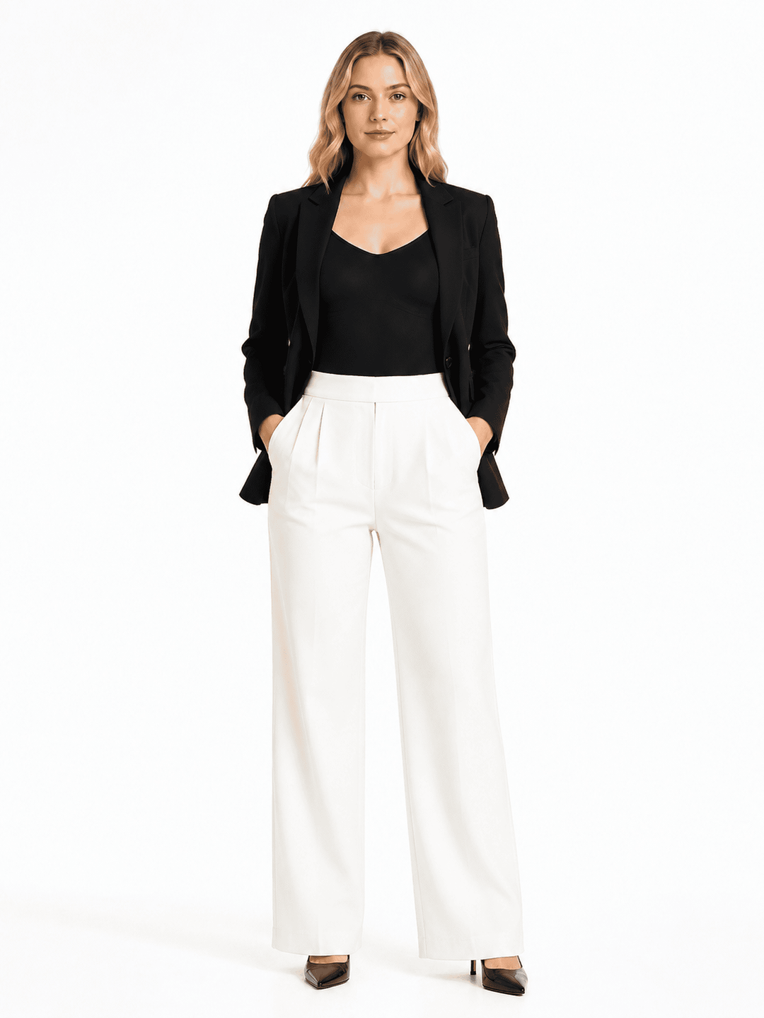 A woman modeling a black blazer over a black top and white wide-leg trousers, standing against a plain white studio background.