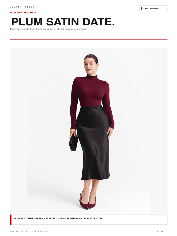 A fashion editorial-style product image showing a woman modeling a plum red satin date night outfit consisting of a long-sleeve mock neck top and a black satin midi skirt, against a clean white background.
