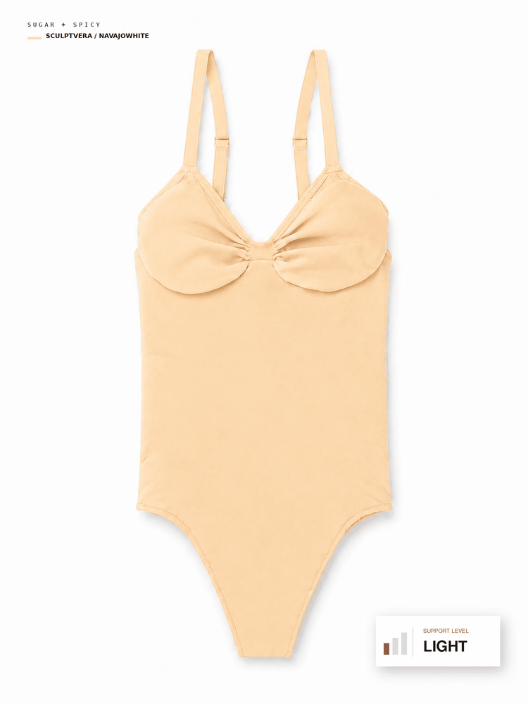 A light peach-beige one-piece bodysuit with a large bow detail at the bust and thin shoulder straps, shown flat against a white background with text labels indicating color and support level.