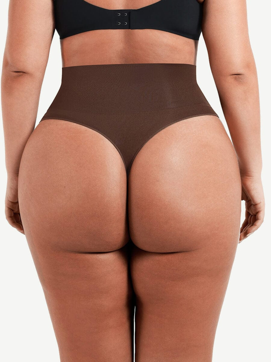 Person wearing brown high-waisted underwear on a plain background