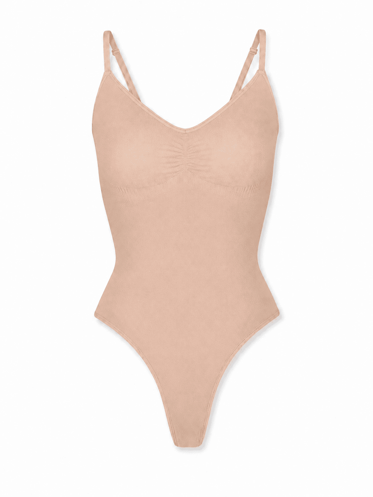 A light peach-beige one-piece bodysuit with thin double shoulder straps and a gathered bust detail, shown against a plain white background.