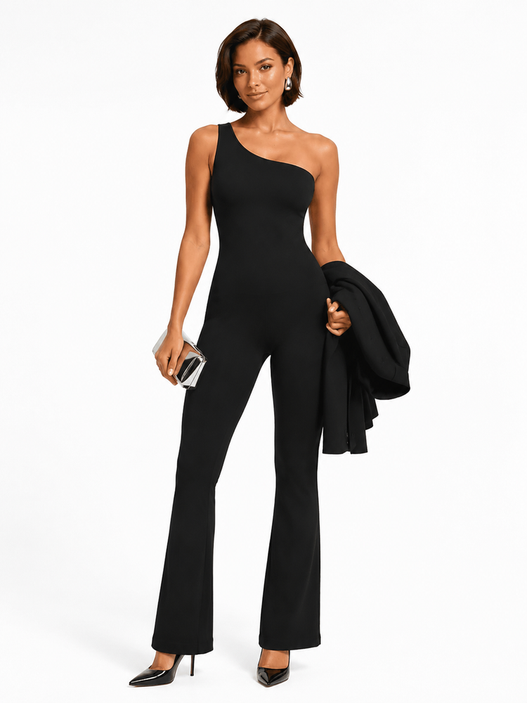 A woman modeling a black one-shoulder flared jumpsuit, holding a black blazer and a small metallic clutch against a plain white studio background.