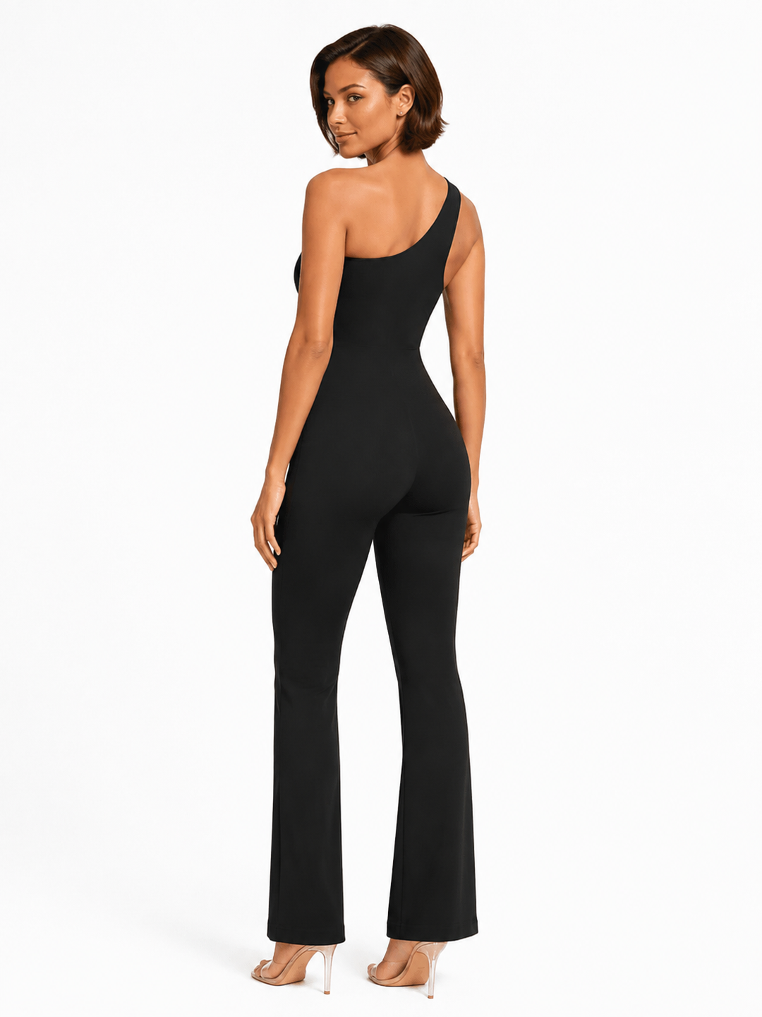 A woman modeling a black one-shoulder flared jumpsuit, shown from a rear three-quarter angle against a plain white studio background.