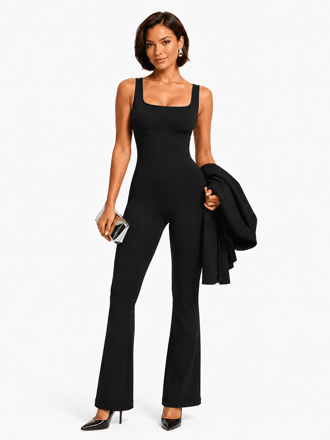 A woman modeling a black sleeveless jumpsuit with a square neckline and wide-leg flared pants, holding a black jacket and a small metallic clutch against a plain light background.