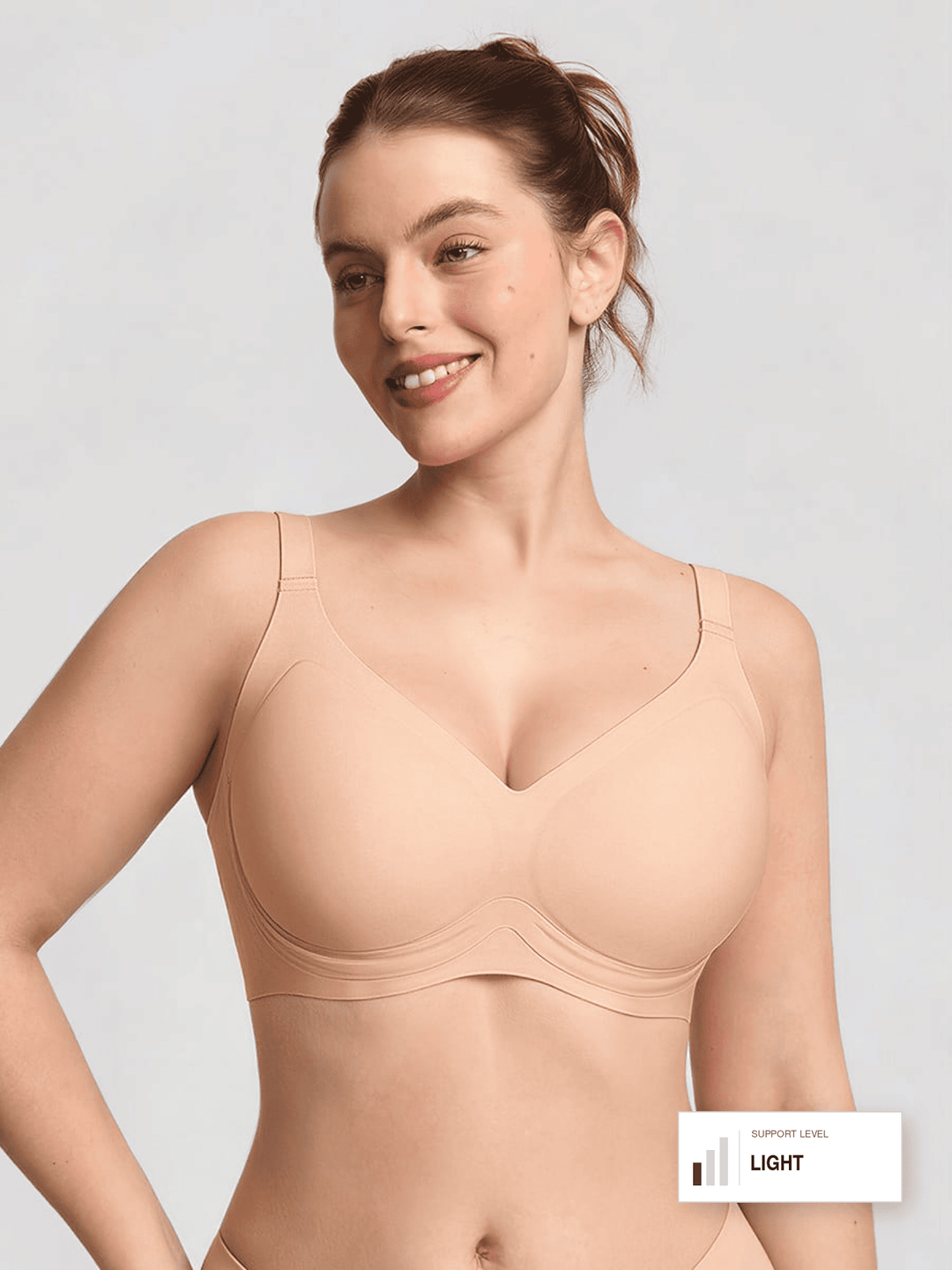 A woman modeling a seamless, supportive underwire bra in a light beige/nude shade against a light gray studio background. A small label in the bottom right corner reads 'SUPPORT LEVEL LIGHT'.