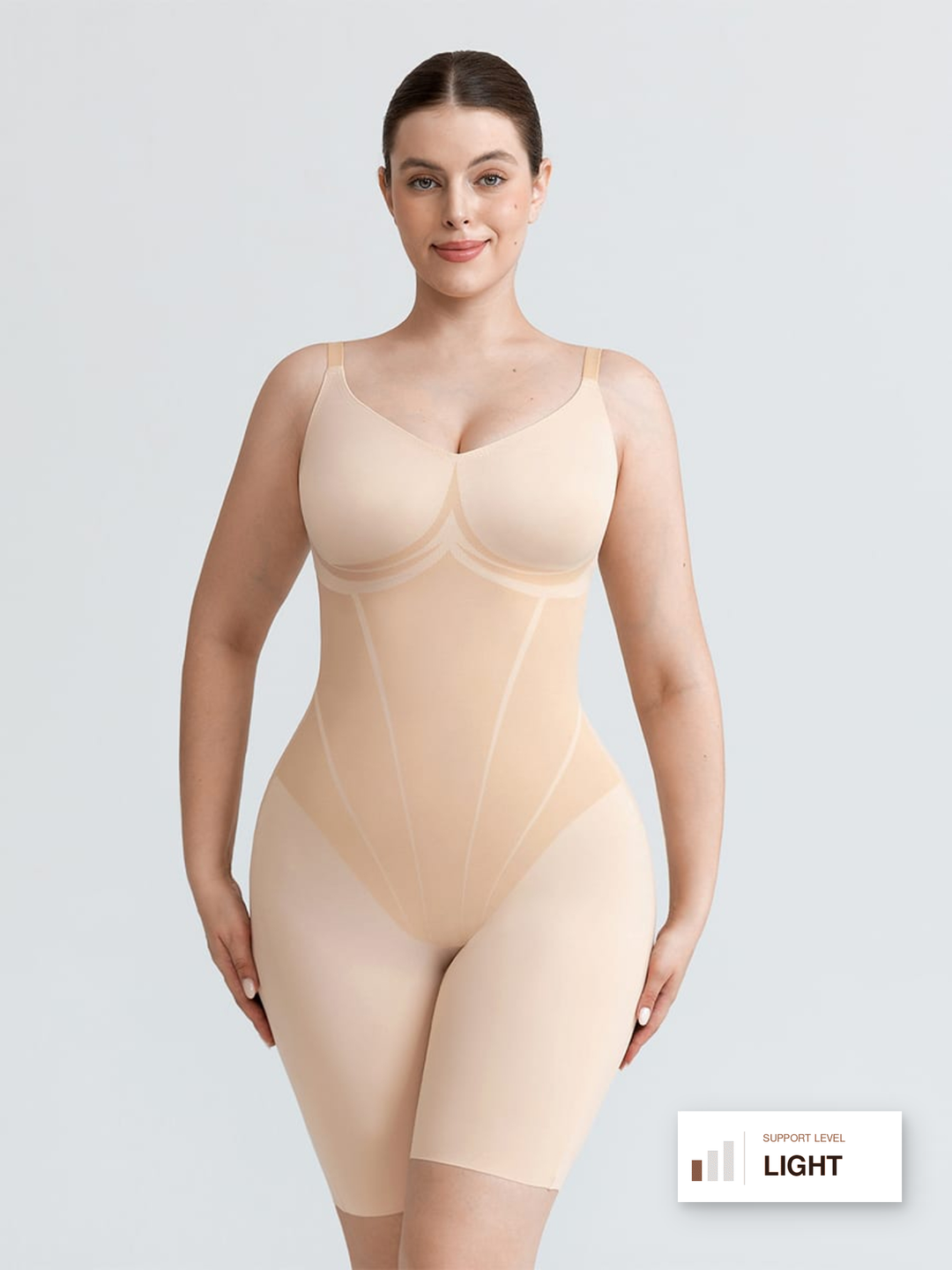 A woman modeling a light beige compression bodysuit with underwire cups and mid-thigh legs against a light gray studio background. A small label in the bottom right corner reads 'SUPPORT LEVEL LIGHT'.