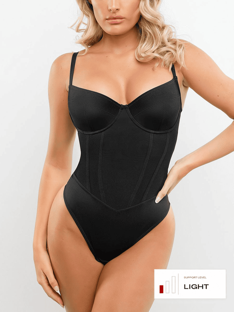A woman modeling a black structured bodysuit with underwire cups and a corset-style front, shown against a light gray studio background. A small label in the lower right reads 'SUPPORT LEVEL LIGHT'.