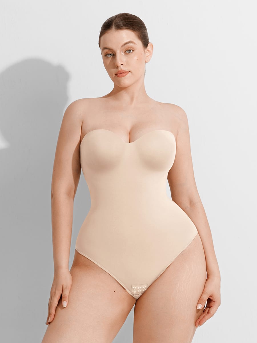 Woman wearing a beige strapless bodysuit against a plain background