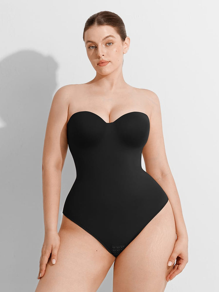 Woman wearing a black strapless bodysuit against a plain background