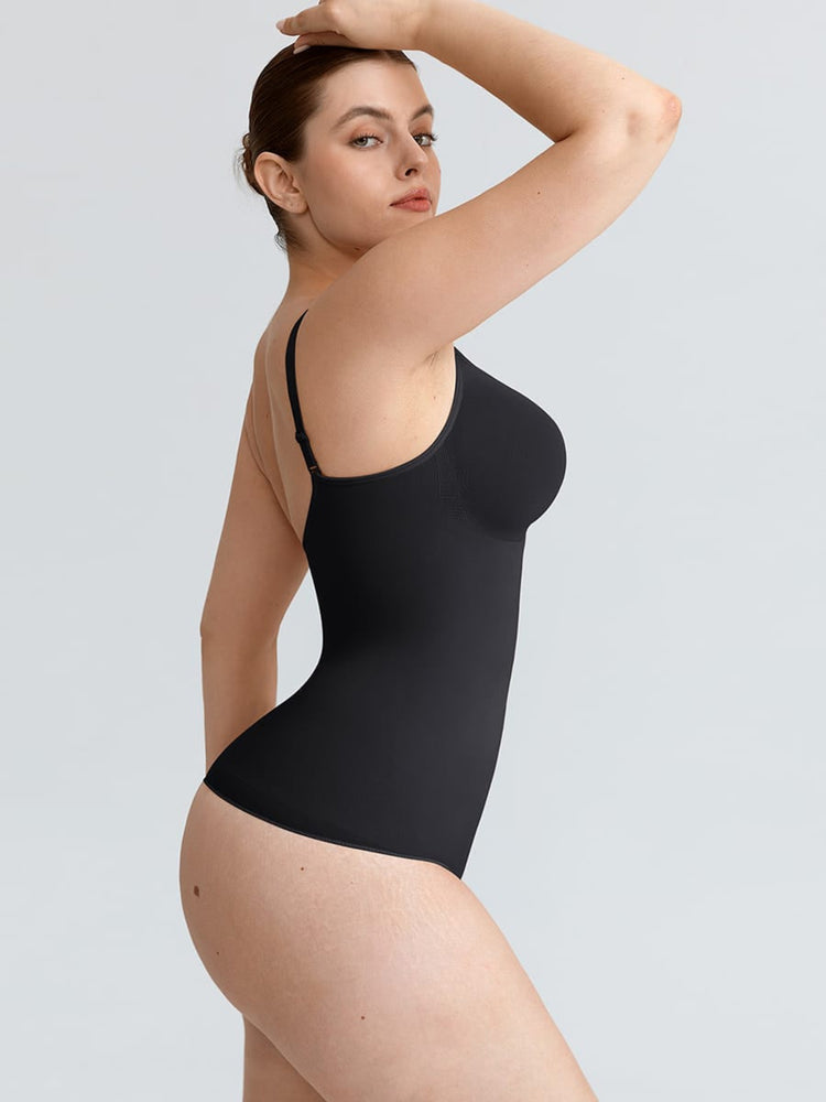 A woman modeling a black one-piece bodysuit with thin shoulder straps and a scoop neckline, shown from a side-back angle against a light gray studio background.