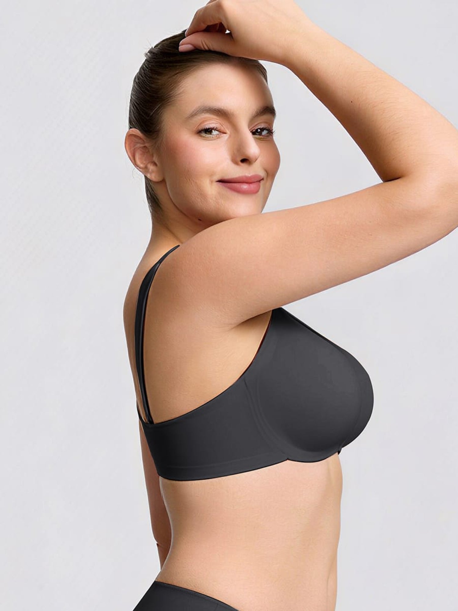 Woman wearing a black bra against a light gray background