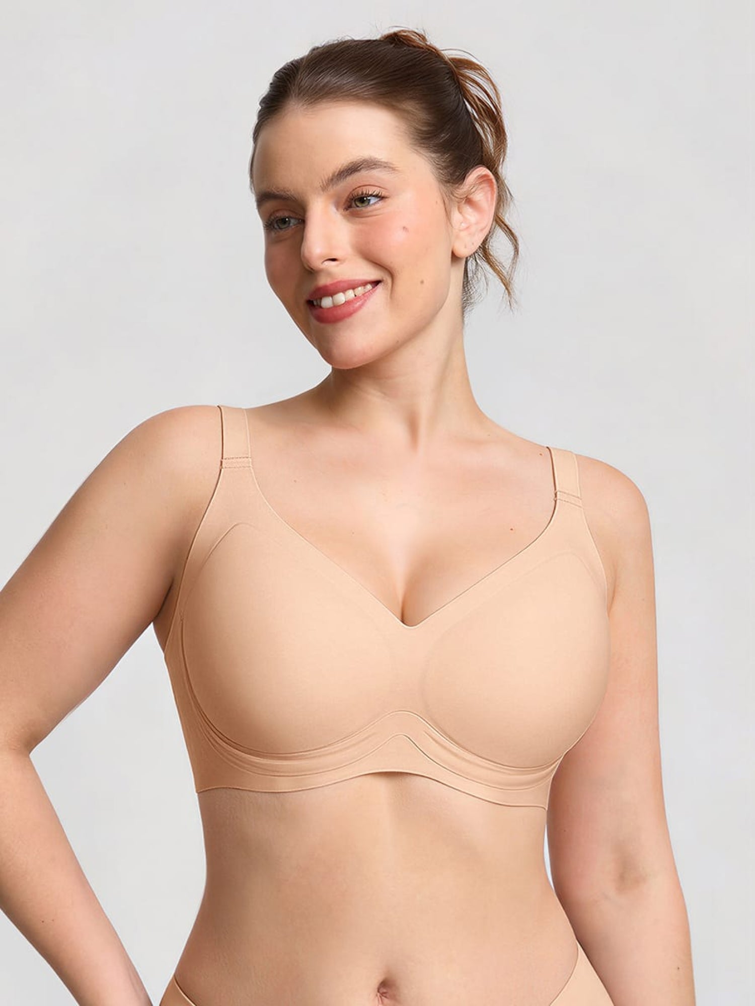 Woman wearing a beige bodysuit against a light gray background