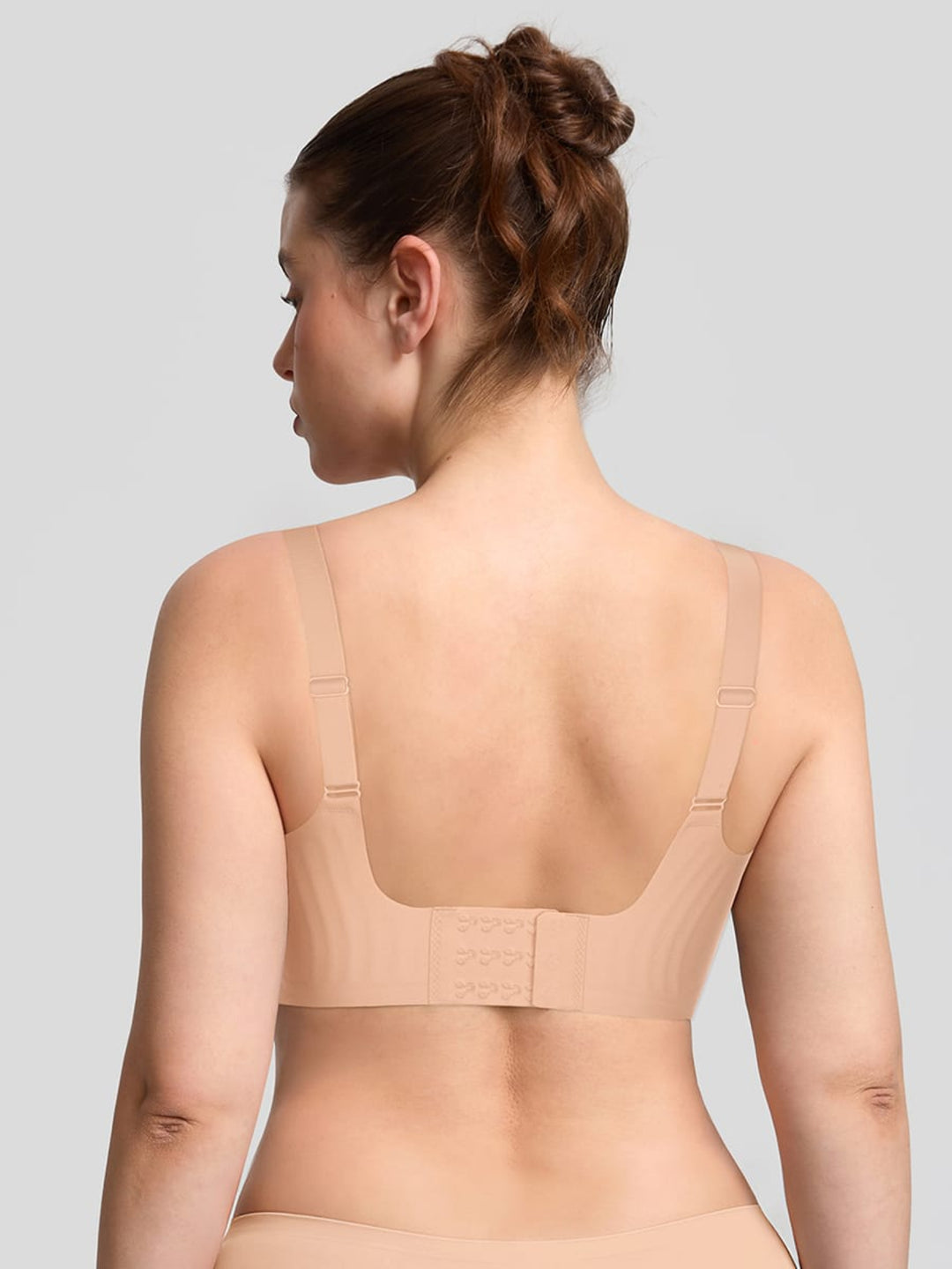 Woman wearing a beige compression garment on a plain background
