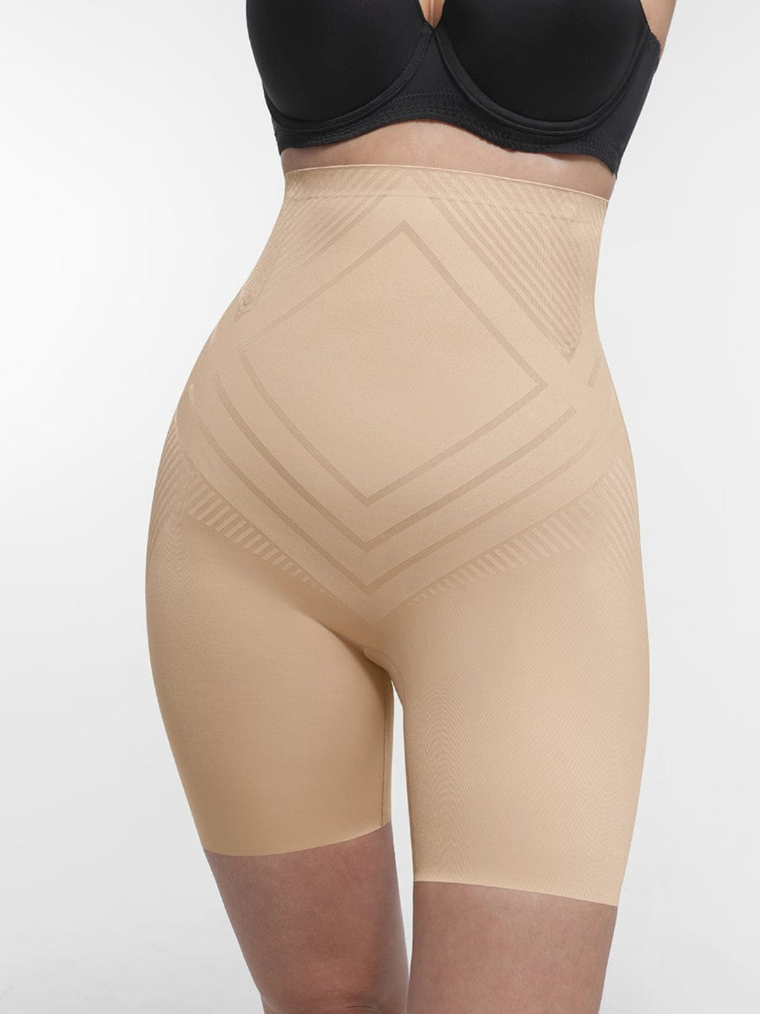 Beige shapewear shorts worn with a black bra on a white background