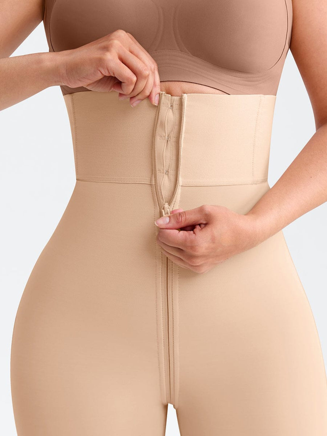 Person wearing a beige shapewear garment with a plain background