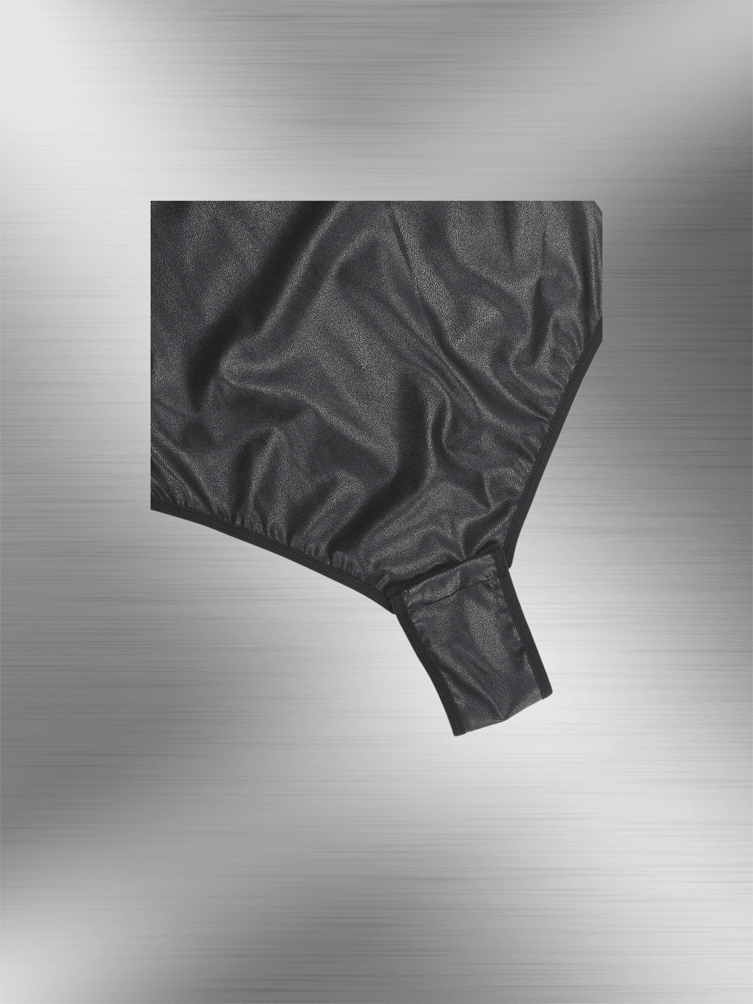 faux leather bodysuit close-up showing glossy black textured fabric and fitted bottom detail
