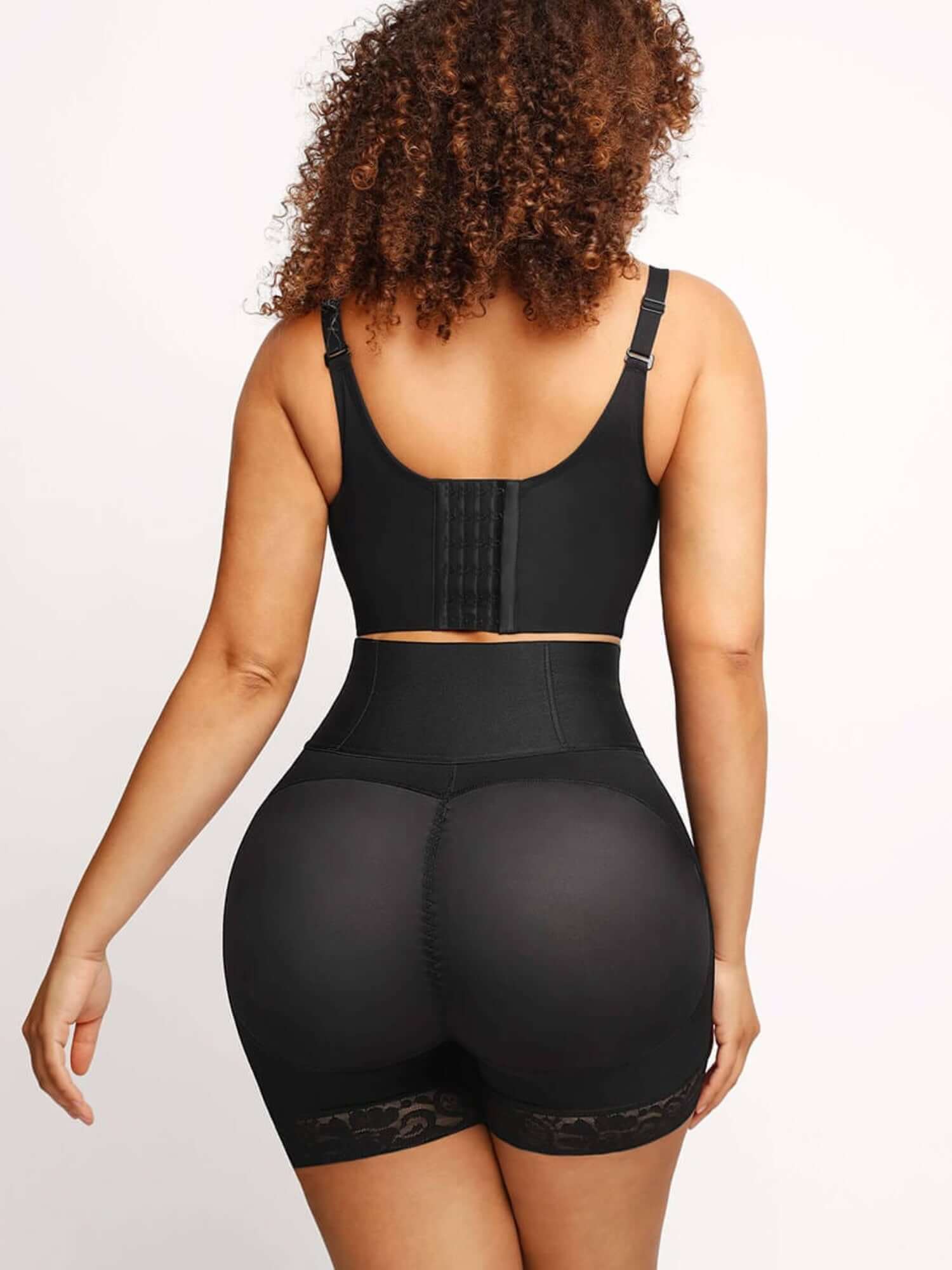 High-waisted shaping shorts for smoothing support and coverage, rear view of black mid-thigh shaper shorts