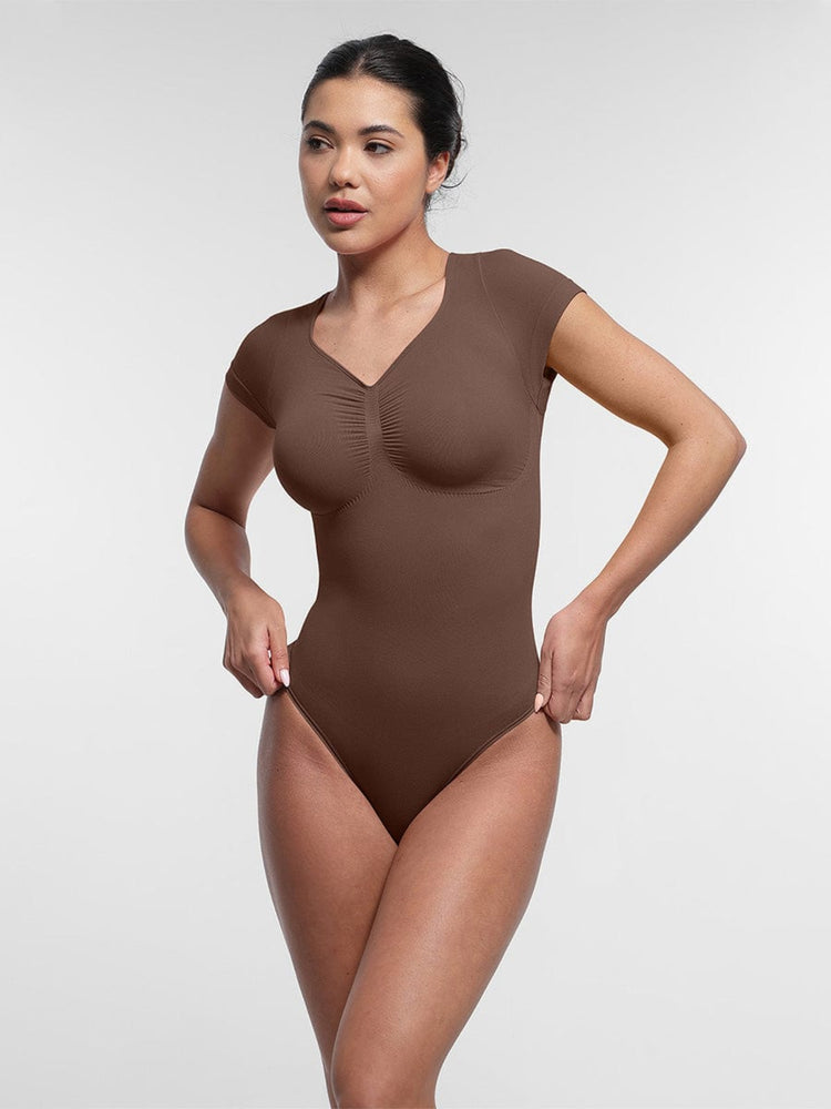 Woman wearing a brown bodysuit against a white background