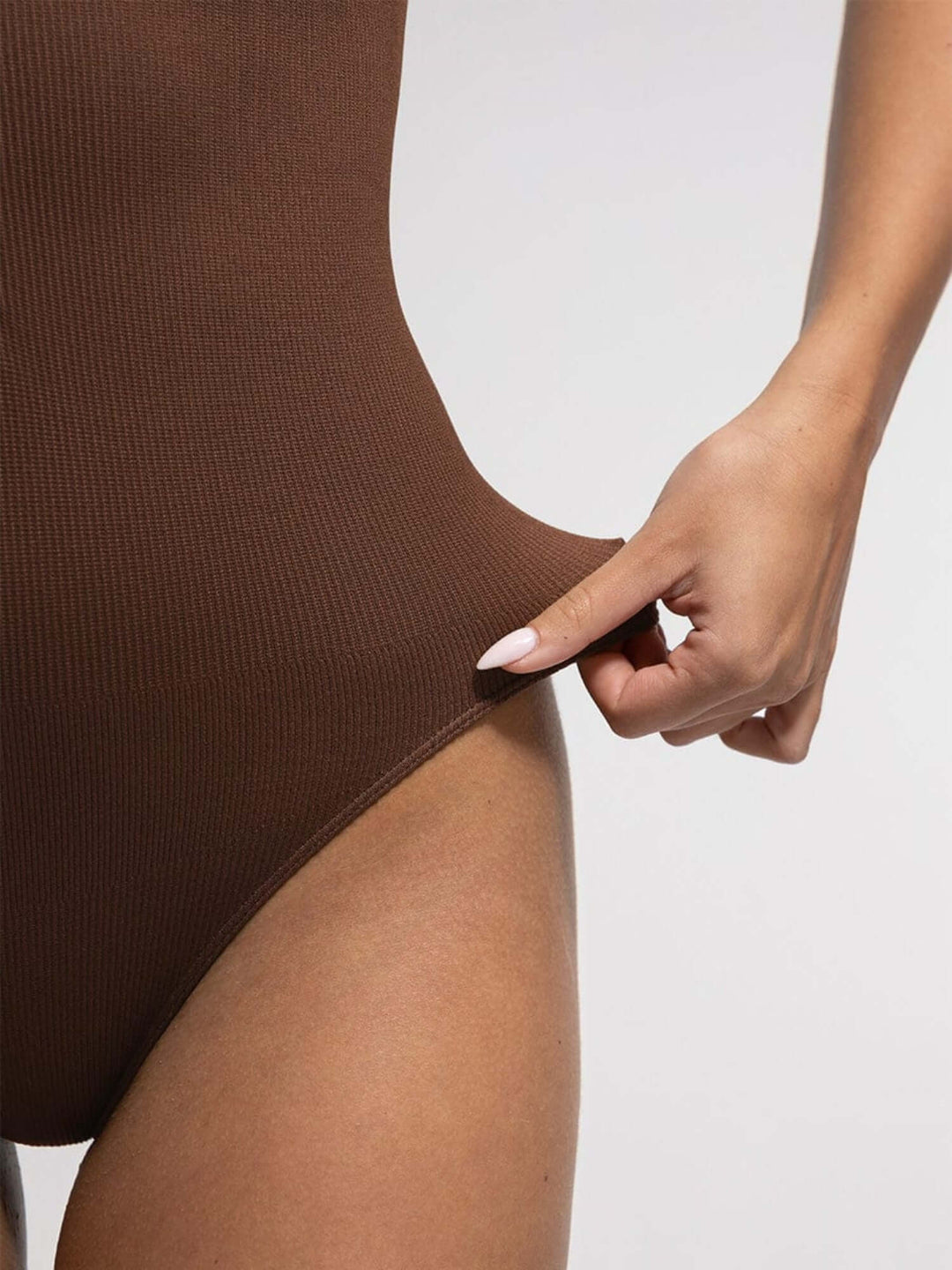 Brown bodysuit worn by a person with a neutral background