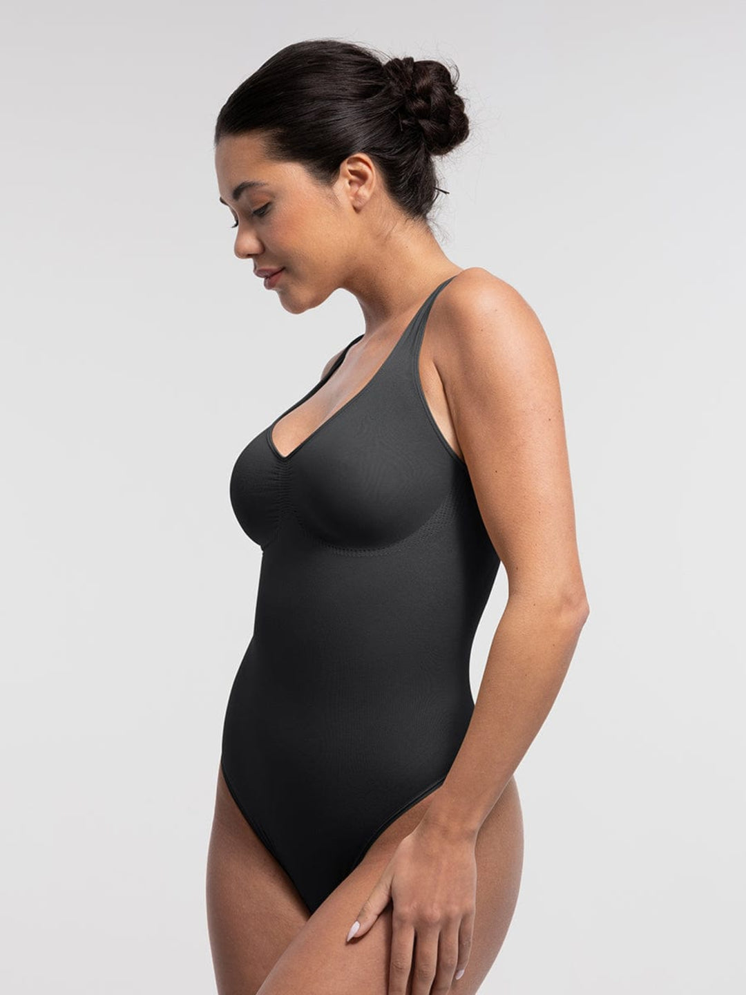 Woman wearing a black bodysuit against a plain background