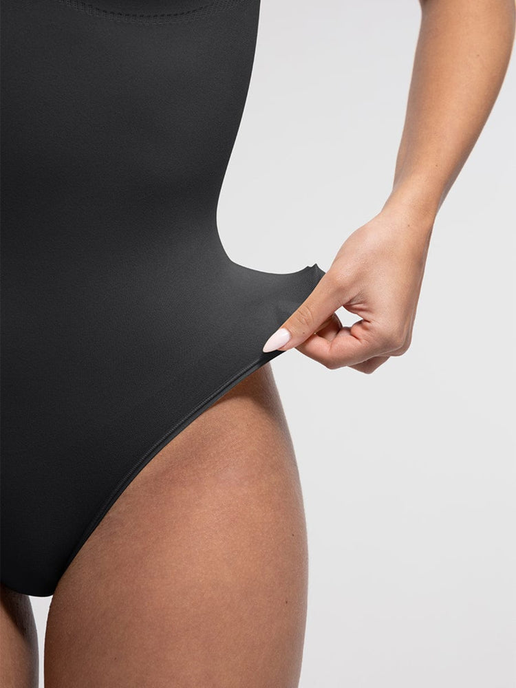 Person wearing a black swimsuit with a plain background