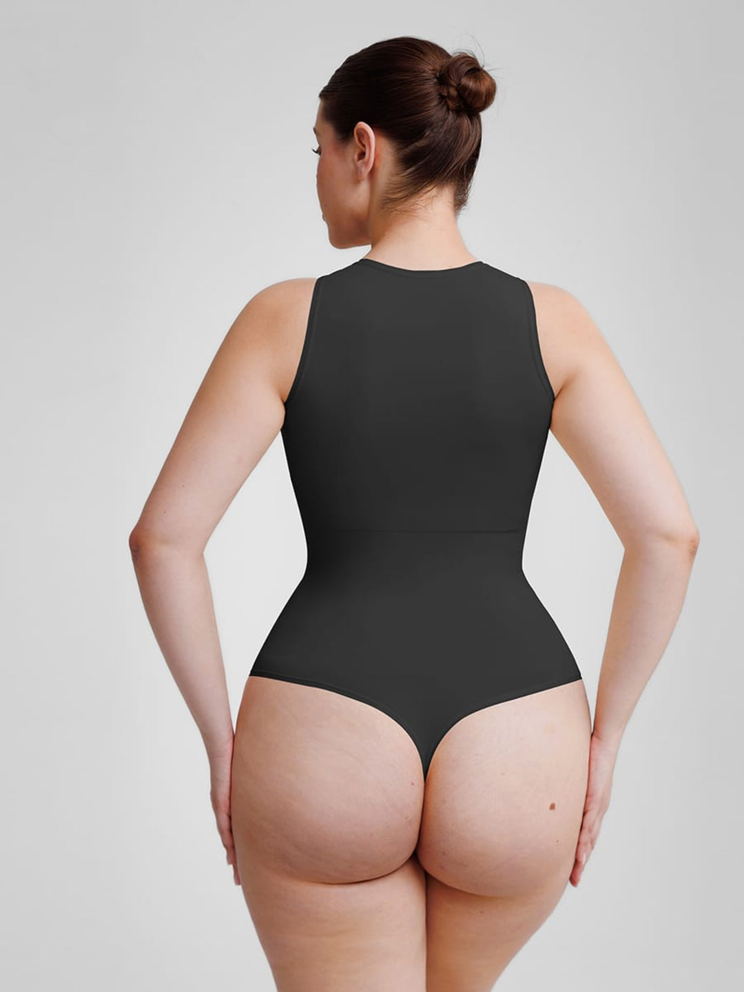 Woman wearing a black bodysuit against a plain background