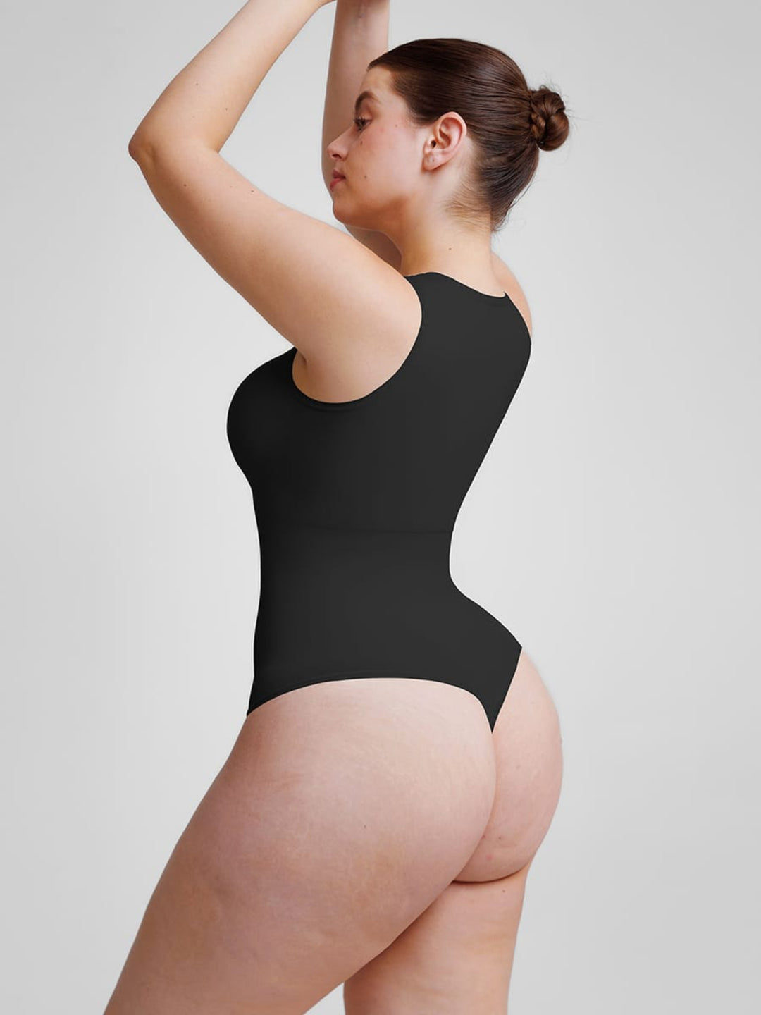 Woman wearing a black bodysuit against a plain background