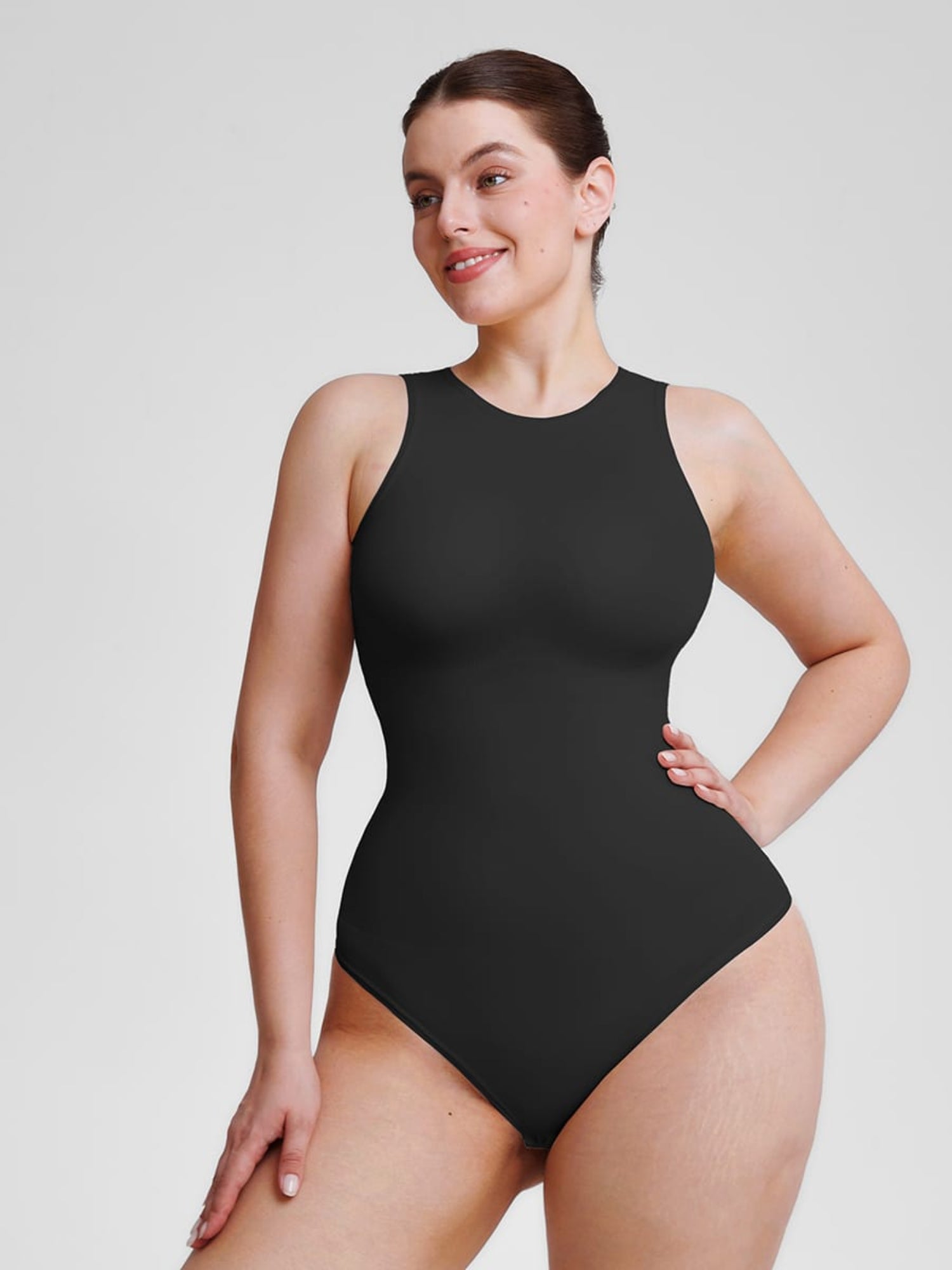 Woman wearing a black bodysuit against a plain background