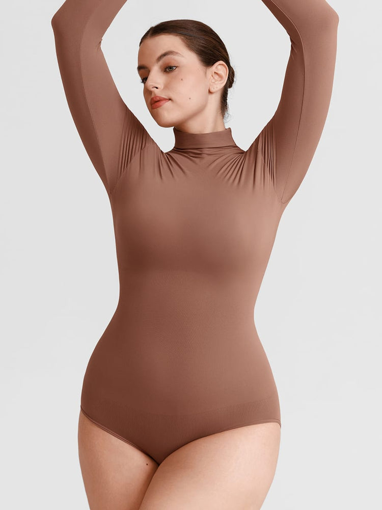 A woman modeling a long-sleeve, high-neck bodysuit in a solid medium brown color, posed with her arms raised against a light gray background.