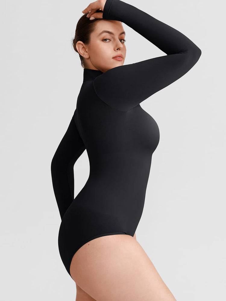 A woman modeling a black long-sleeve bodysuit against a light gray studio background.