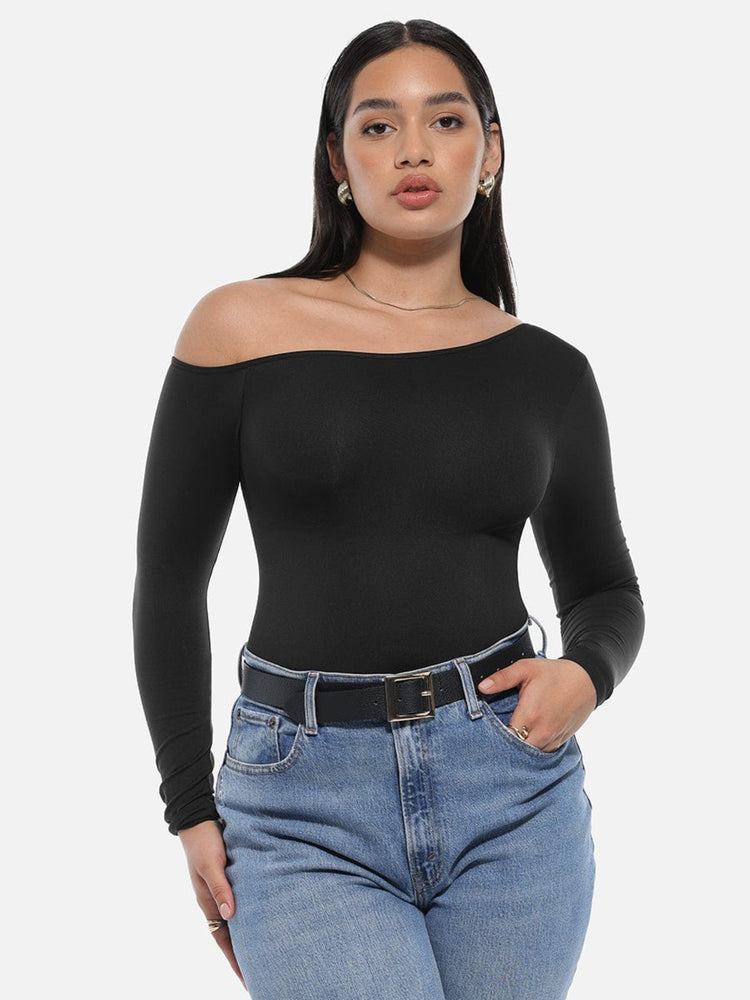 Woman wearing a black off-shoulder top and blue jeans on a white background