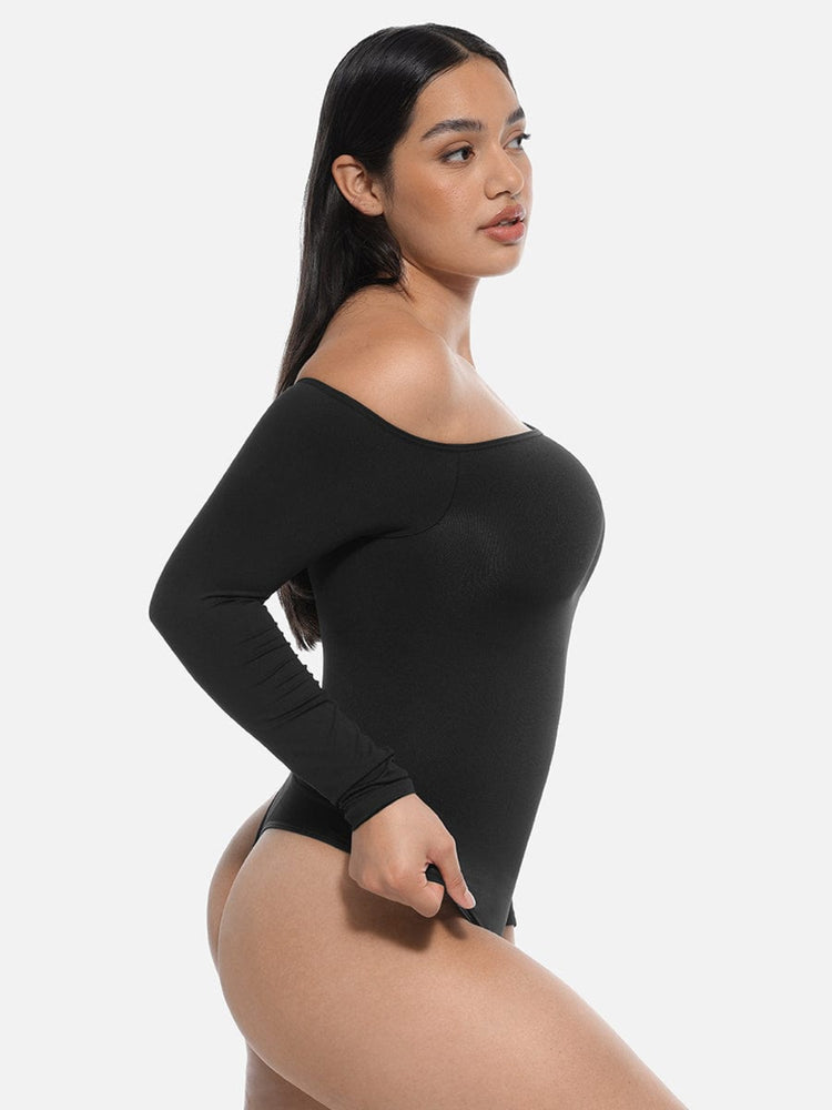 Woman wearing a black long-sleeve bodysuit against a white background