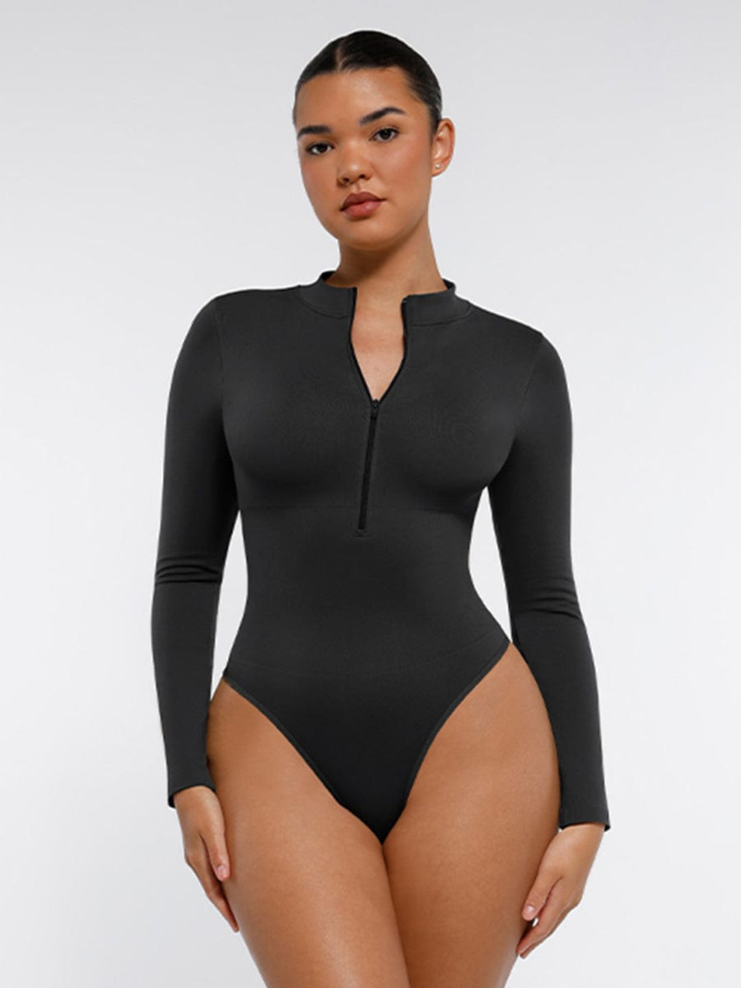Woman wearing a black long-sleeve swimsuit against a white background