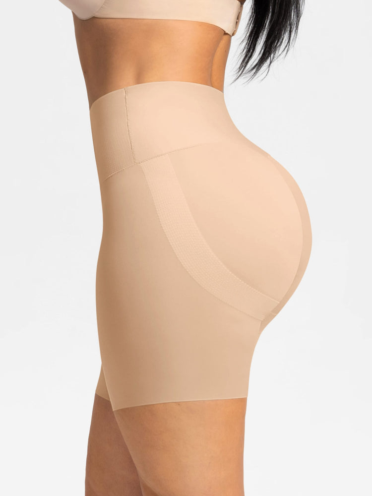 Side view of a model wearing high-waisted beige shapewear shorts against a plain light gray background.
