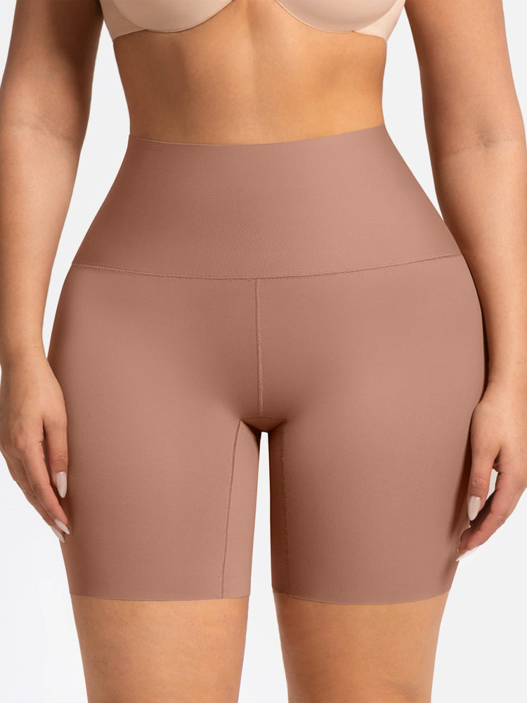 A close-up of a model wearing high-waisted, seamless athletic biker shorts in a dusty rose or mauve color, paired with a matching sports bra against a light gray background.