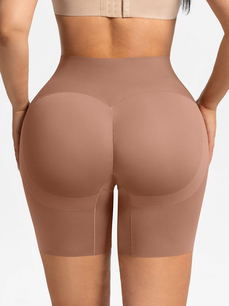 Rear view of a model wearing high-waisted shapewear shorts in a nude beige color, paired with a matching bralette against a light gray background.