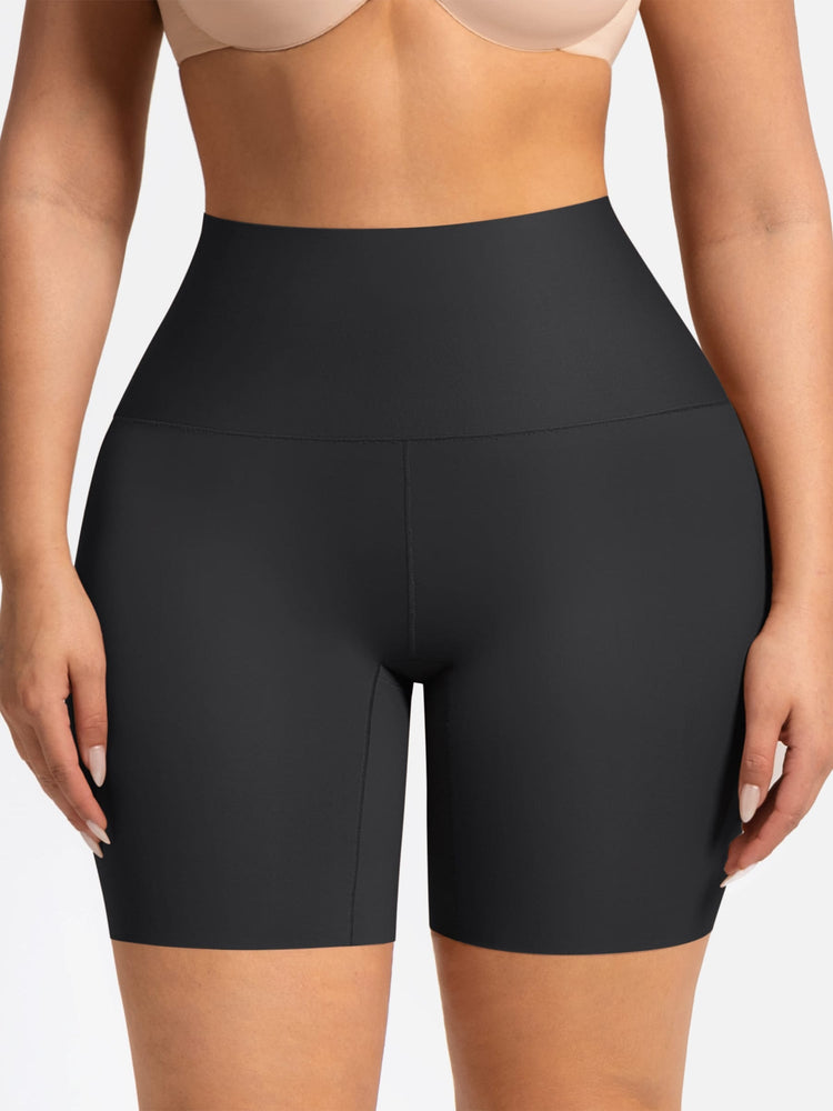 A close-up of a model wearing high-waisted black athletic biker shorts against a plain light background.