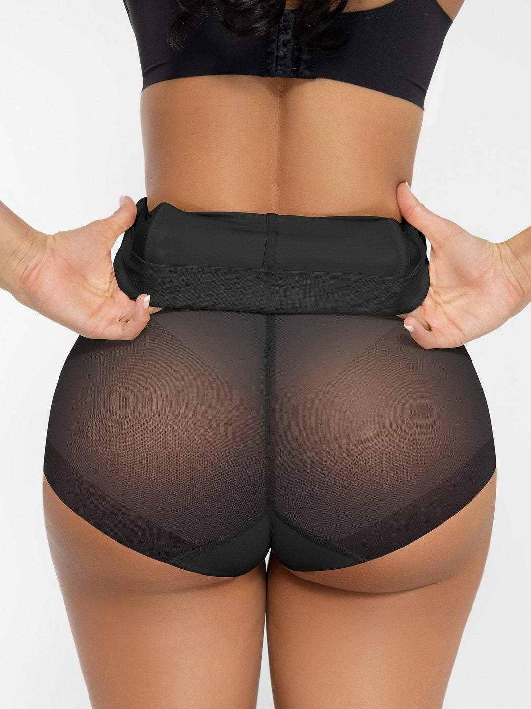 Person wearing sheer black shorts with a black waistband on a white background
