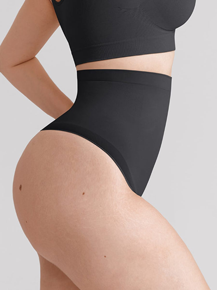 Close-up of a model wearing black high-waisted briefs and a matching black sports bra against a light gray background.